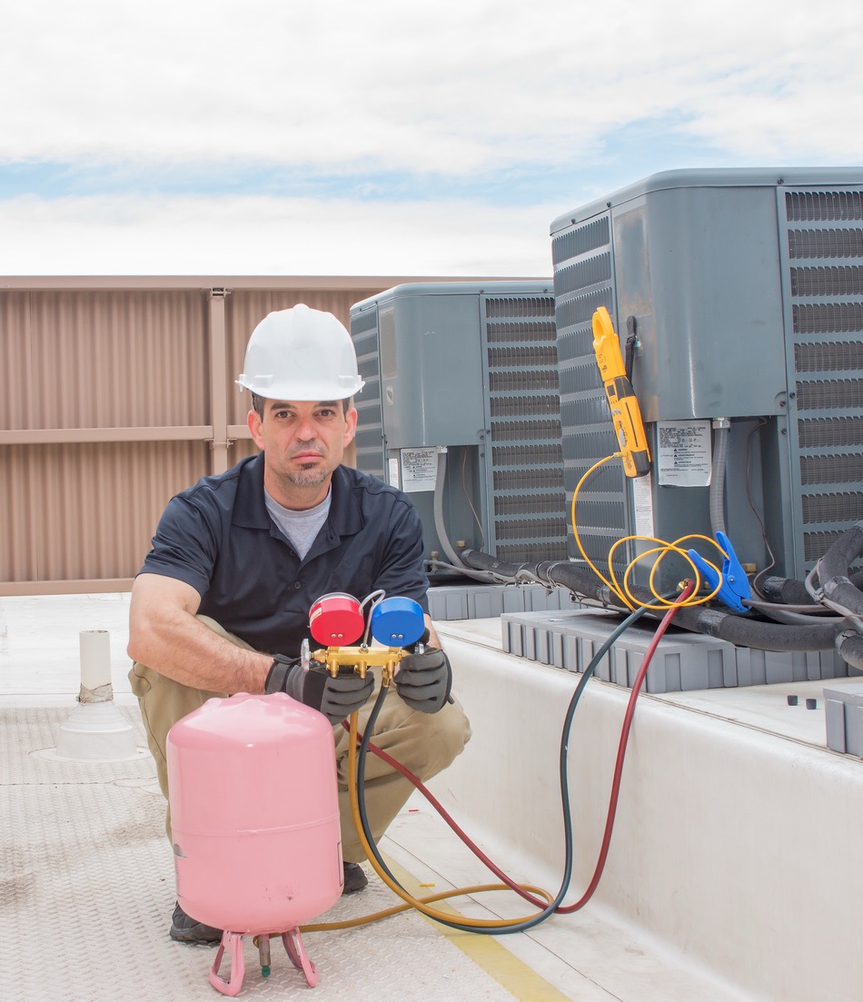 HVAC technician servicing AC unit on rooftop